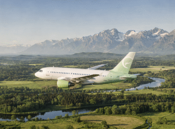 An environmentally conscious airplane flying over a vibrant green landscape with clear skies, representing efforts to reduce carbon emissions.